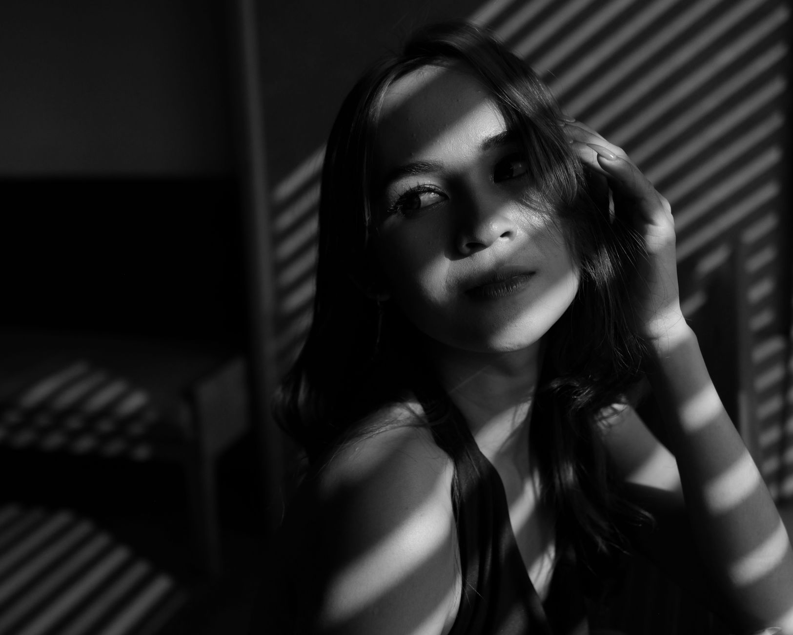 Potret artistik hitam putih seorang wanita dengan pencahayaan dan bayangan dramatis yang diambil di Jakarta.
