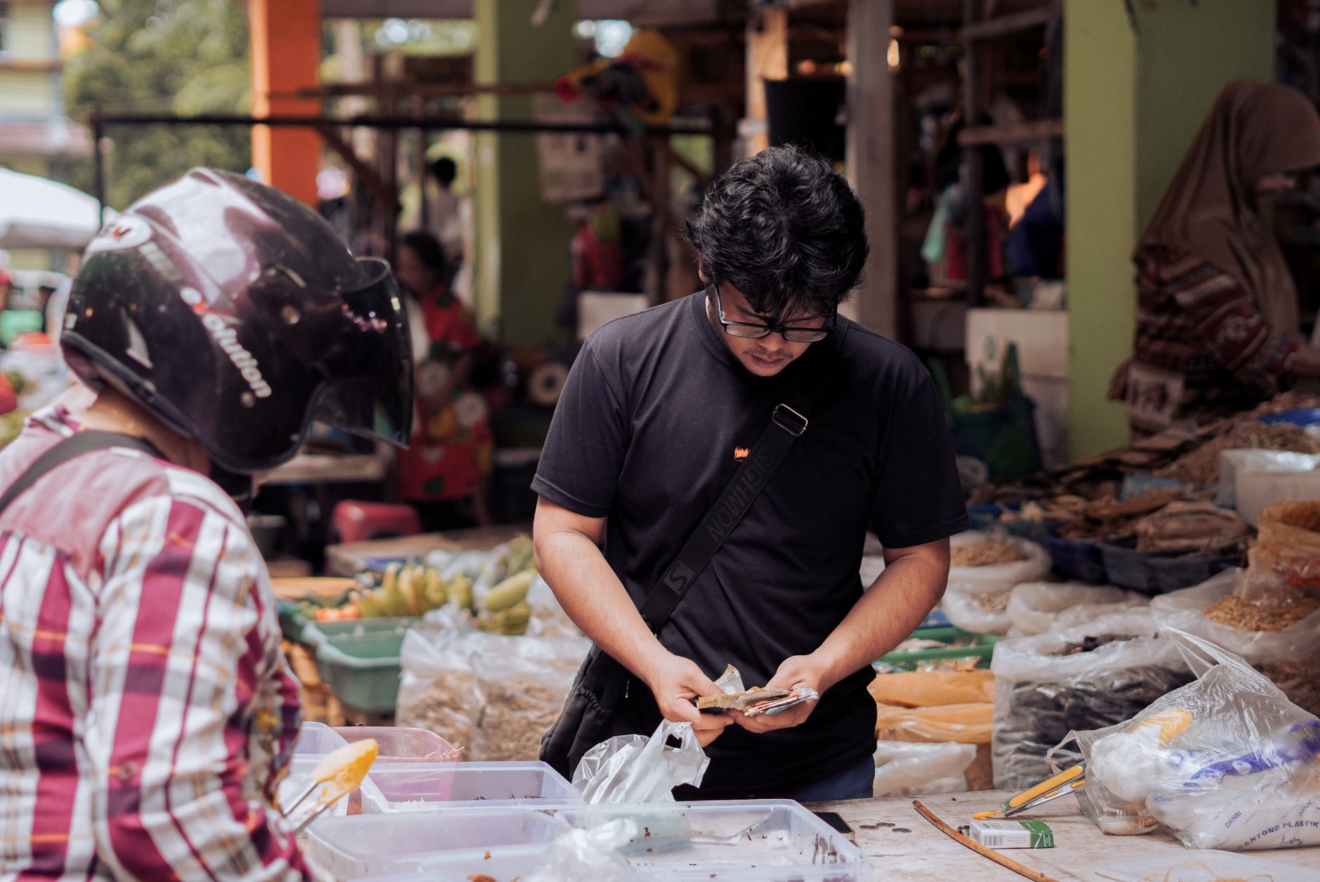 Seorang pria menghitung uang di pasar jalanan yang ramai di Pontianak, Indonesia.