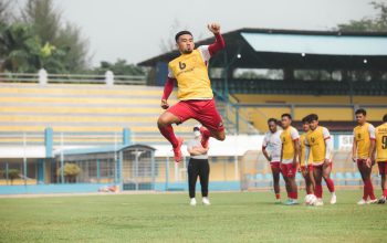 Pemain sepak bola berlatih di lapangan yang cerah di Jakarta, menampilkan atletisme dan kerja tim.