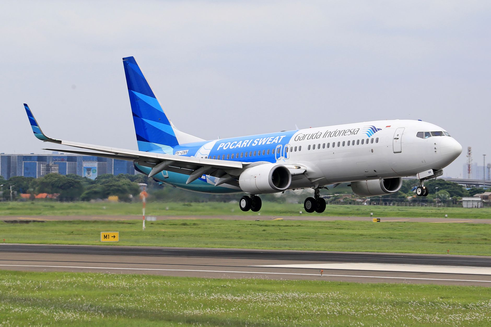 Pesawat Garuda Indonesia yang lepas landas dari landasan, menampilkan penerbangan modern.