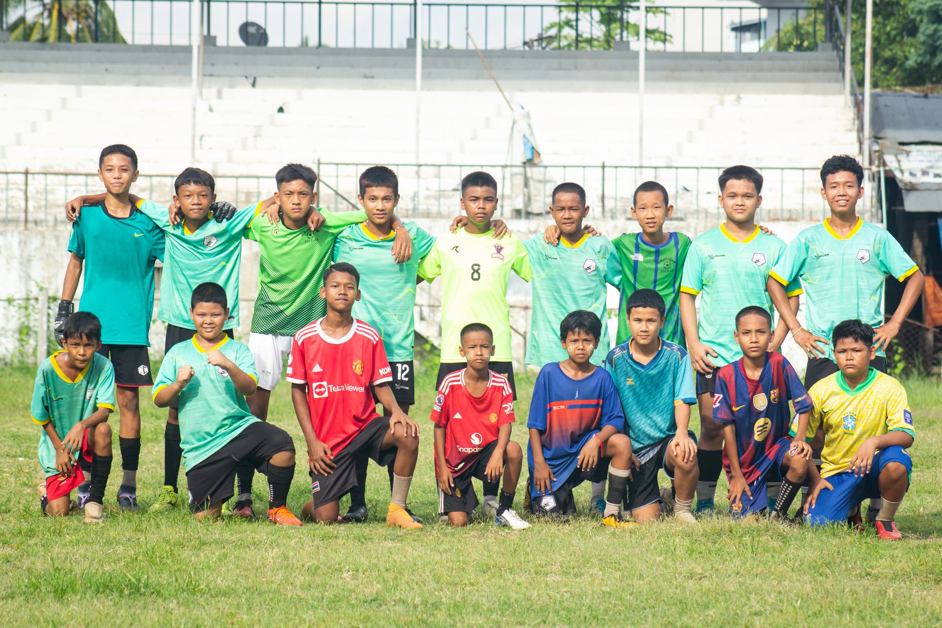 Sekelompok anak laki-laki berpose sebagai tim sepak bola di lapangan di Myawaddy, Myanmar.