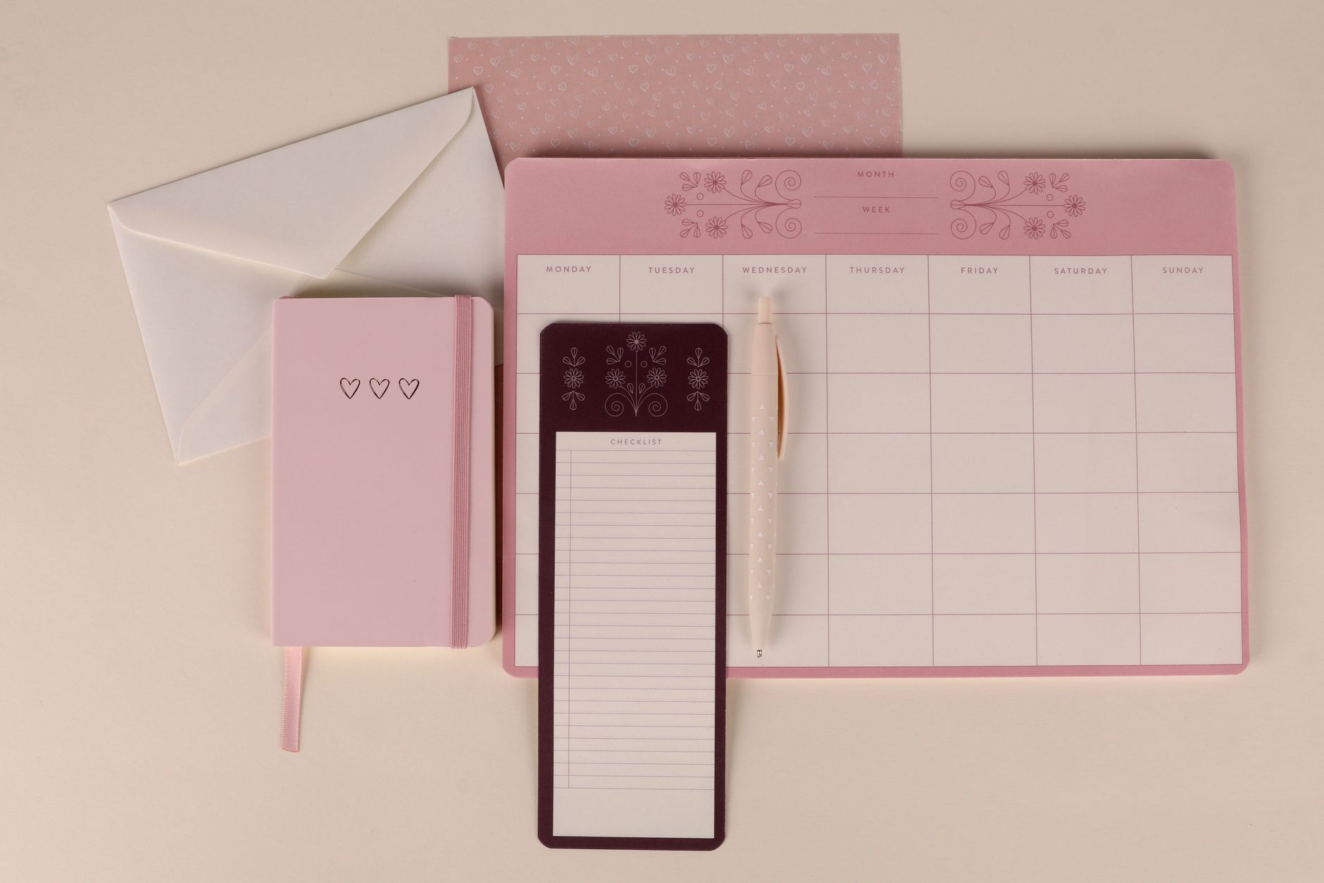 Susunan alat tulis pink yang elegan dengan perencana, buku catatan, dan kertas daftar, sempurna untuk pengorganisasian.