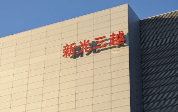 Tampilan eksterior sebuah gedung komersial modern di Taipei yang menampilkan papan nama khas berbahasa Mandarin.