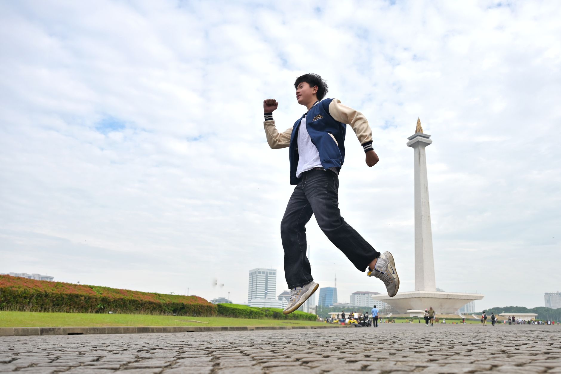 Seorang remaja melompat dengan penuh semangat di depan monumen Monas di Jakarta, menangkap semangat masa muda.