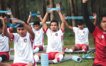 Sekelompok pemain sepak bola muda berlatih dengan band resistensi selama latihan di luar ruangan.
