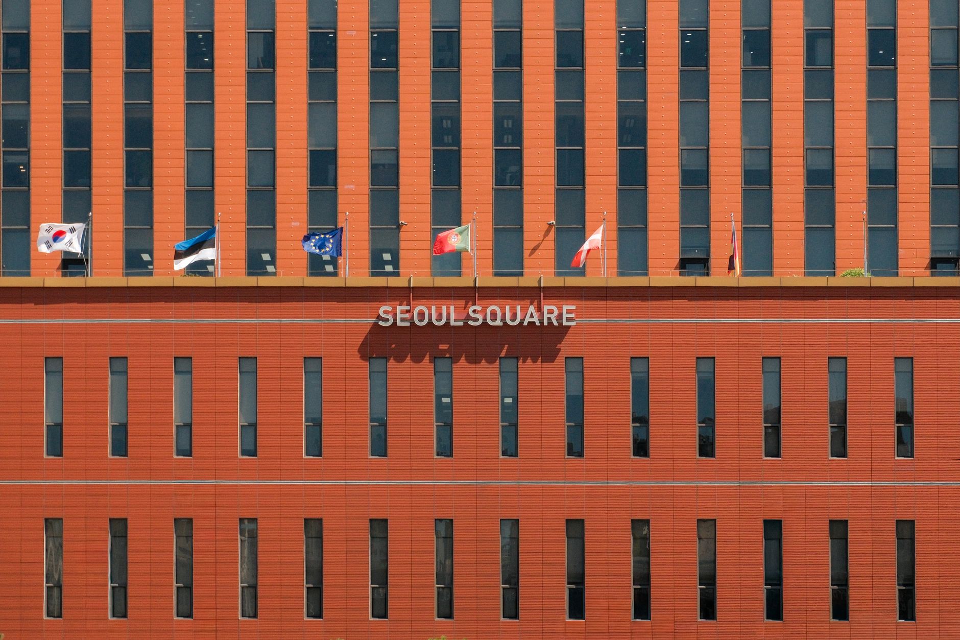 Fasad merah Seoul Square dengan berbagai bendera internasional yang dipajang.