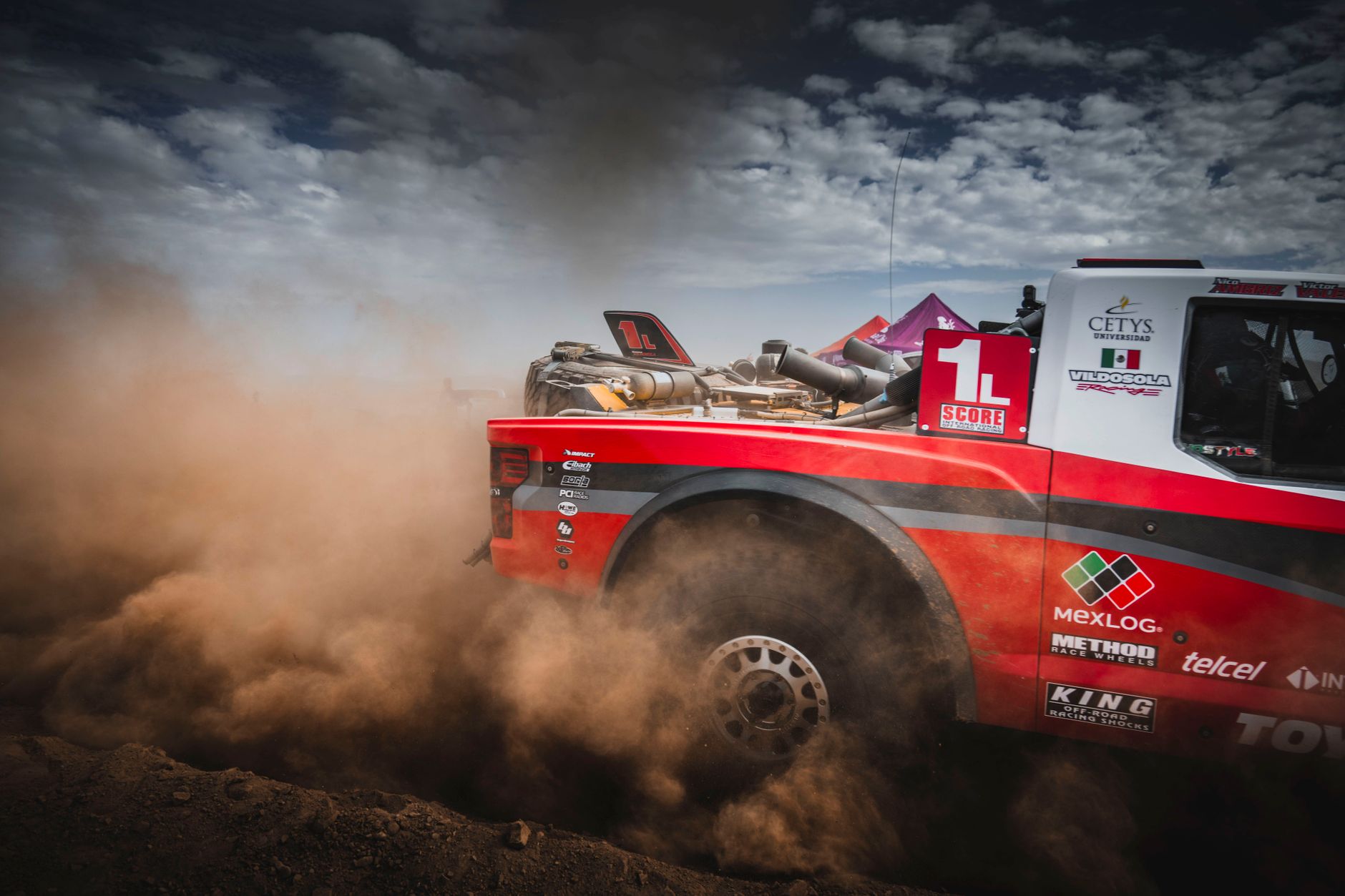 Truk balap off-road berkecepatan tinggi menimbulkan debu di Baja California.