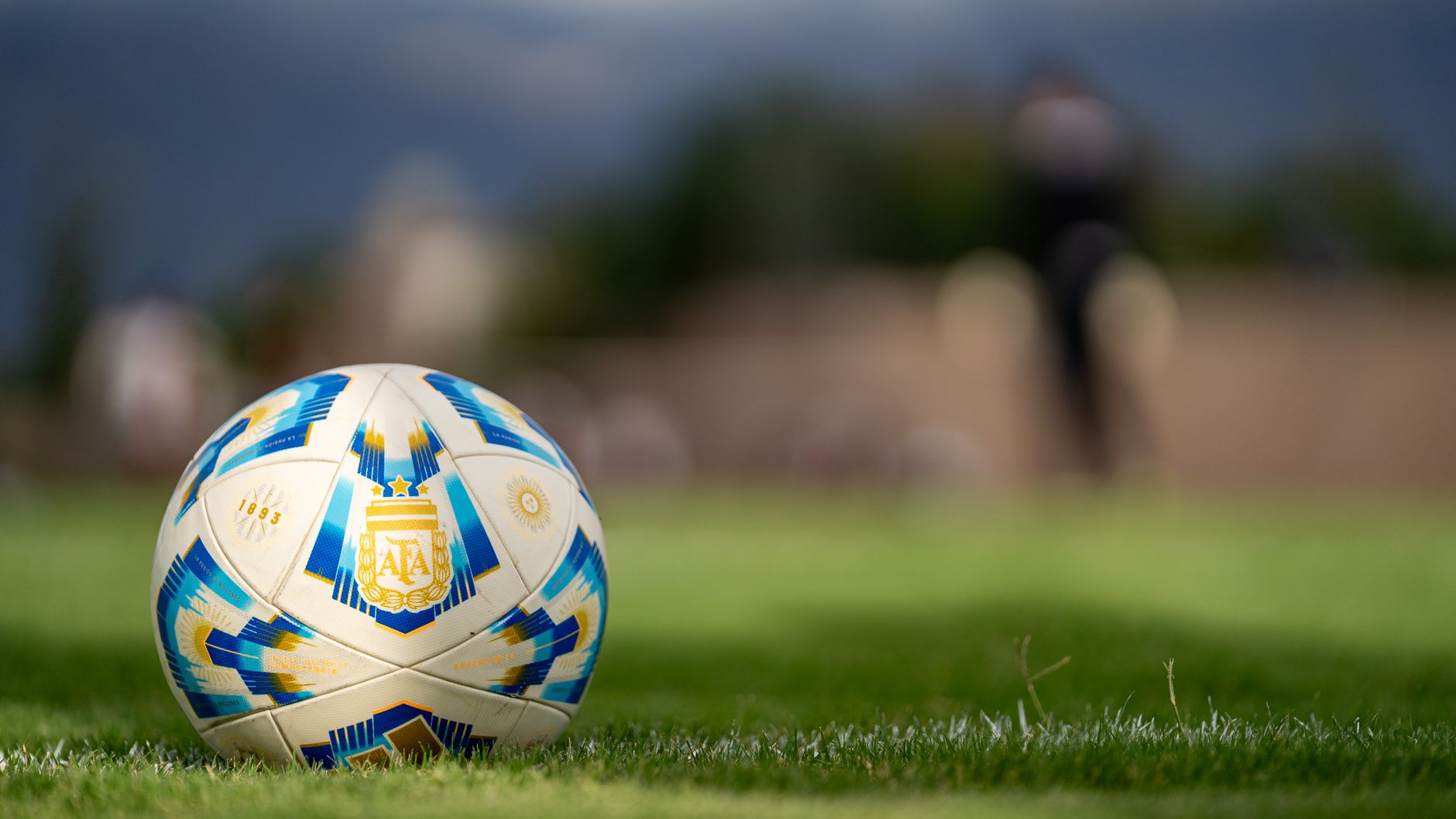 Close-up bola sepak resmi Argentina yang berada di lapangan hijau dengan latar belakang kabur.
