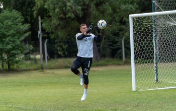 Penjaga gawang menangkap bola sepak saat latihan di lapangan terbuka.