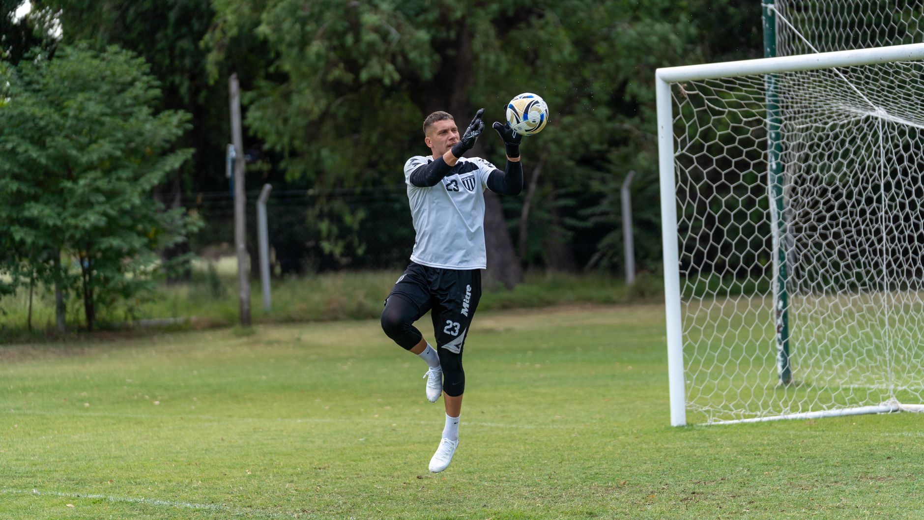 Penjaga gawang menangkap bola sepak saat latihan di lapangan terbuka.