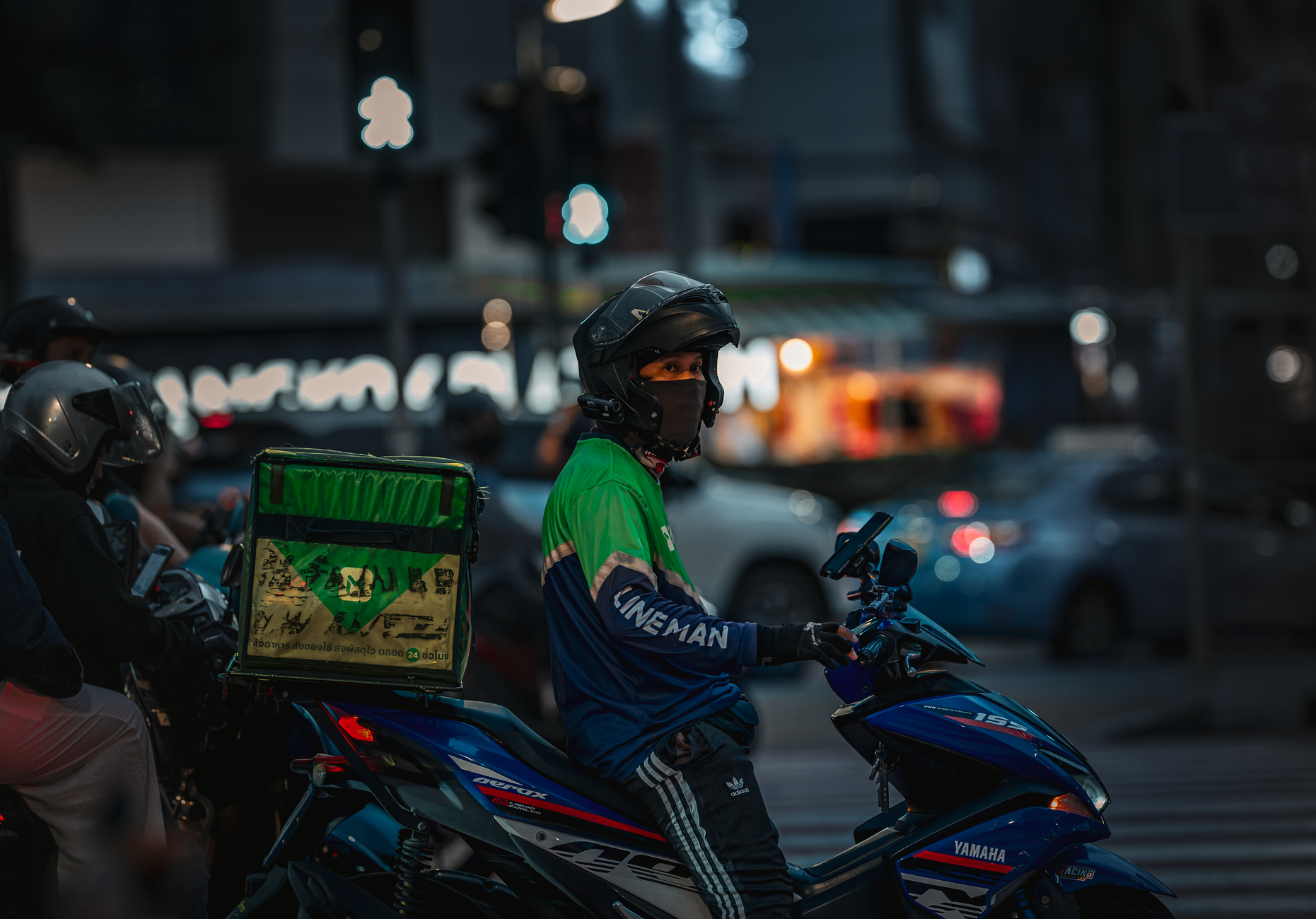 Pengantar makanan menggunakan sepeda motor di malam hari di Bangkok, Thailand.