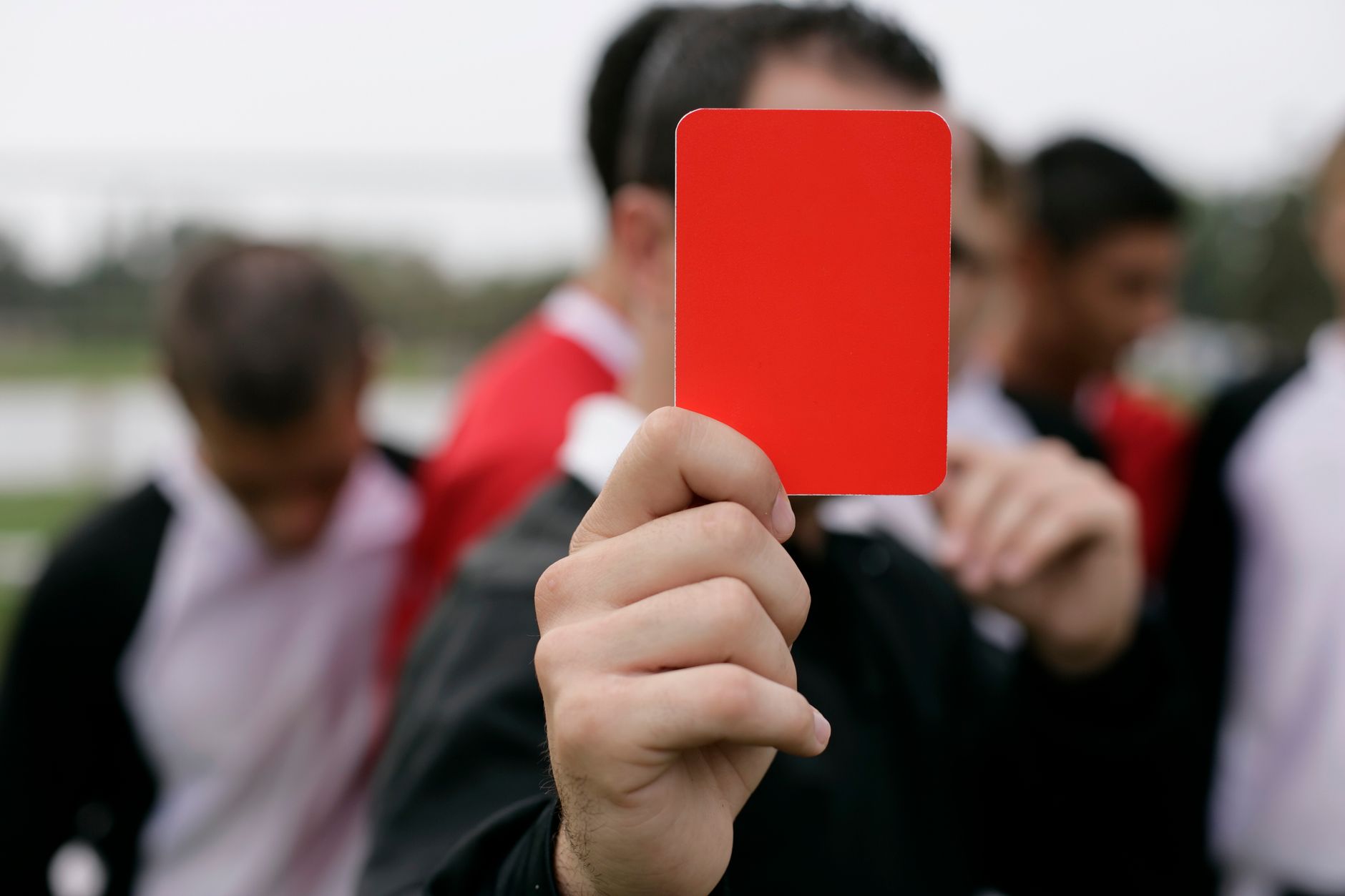 Wasit menunjukkan kartu merah kepada pemain selama pertandingan sepak bola di luar ruangan.