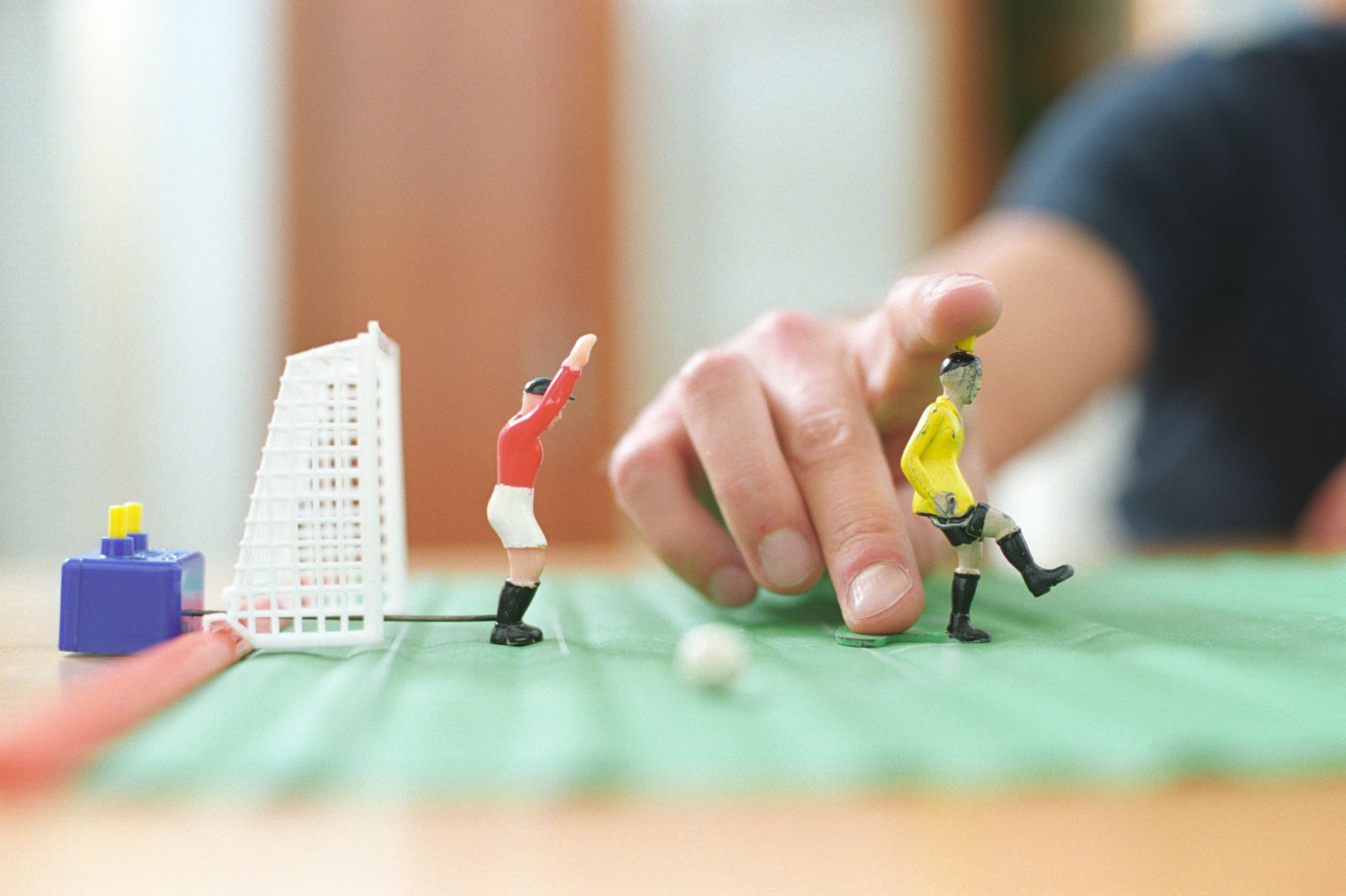 Dekat tangan yang memanipulasi mainan sepak bola meja selama permainan yang menyenangkan.