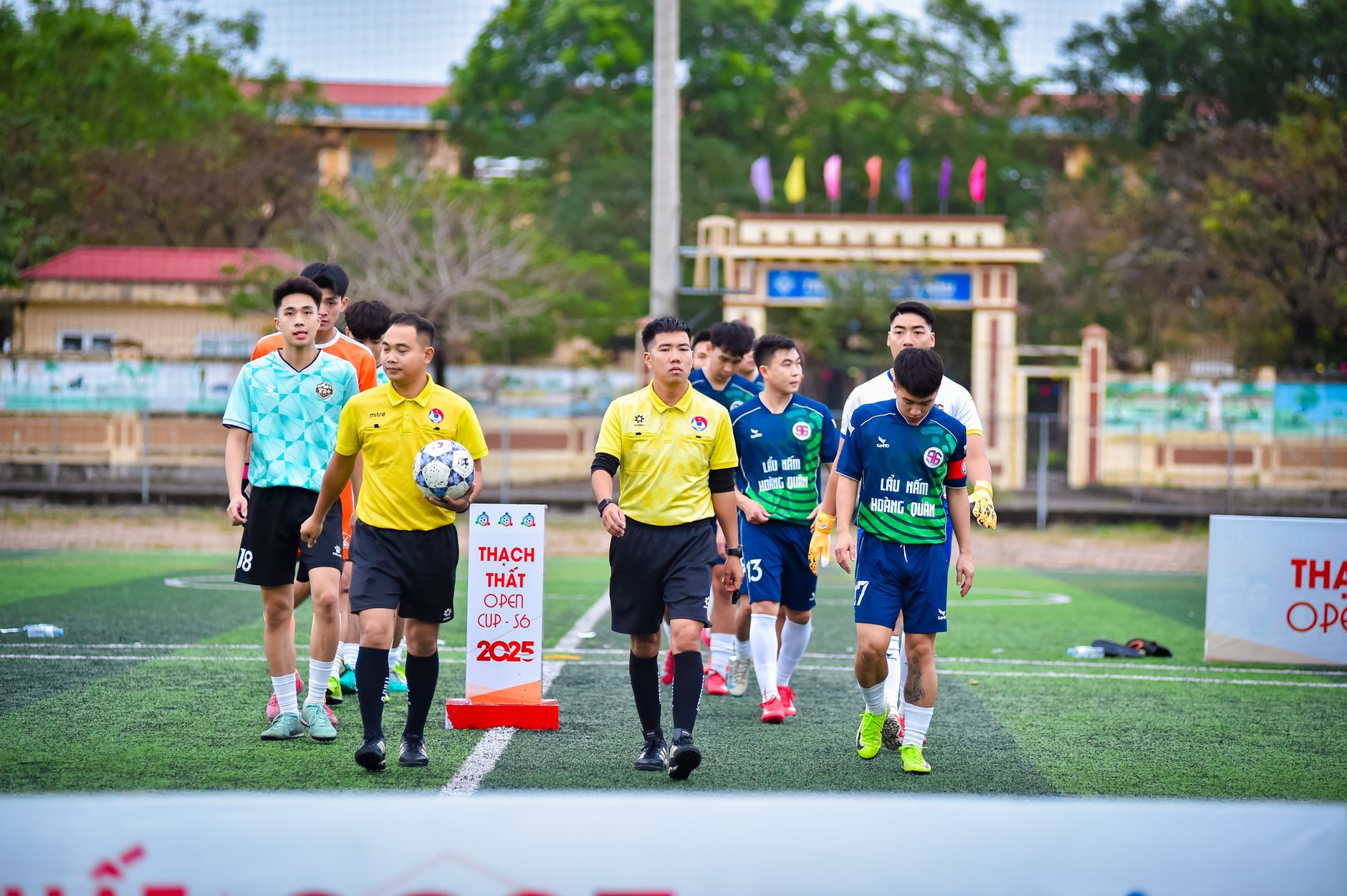 Tim sepak bola memasuki lapangan untuk Piala Terbuka Thạch Thất 2025 di Hà Nội, Vietnam.