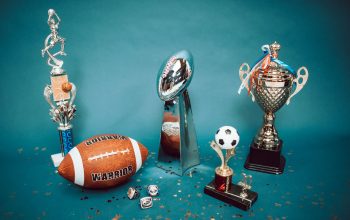 Koleksi trofi olahraga dan barang memorabilia yang mewakili pencapaian dan kesuksesan di latar belakang biru.