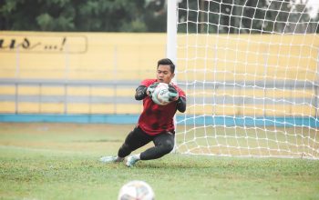 Seorang kiper sepak bola melakukan penyelamatan dinamis selama pertandingan di luar ruangan di Jakarta, Indonesia.