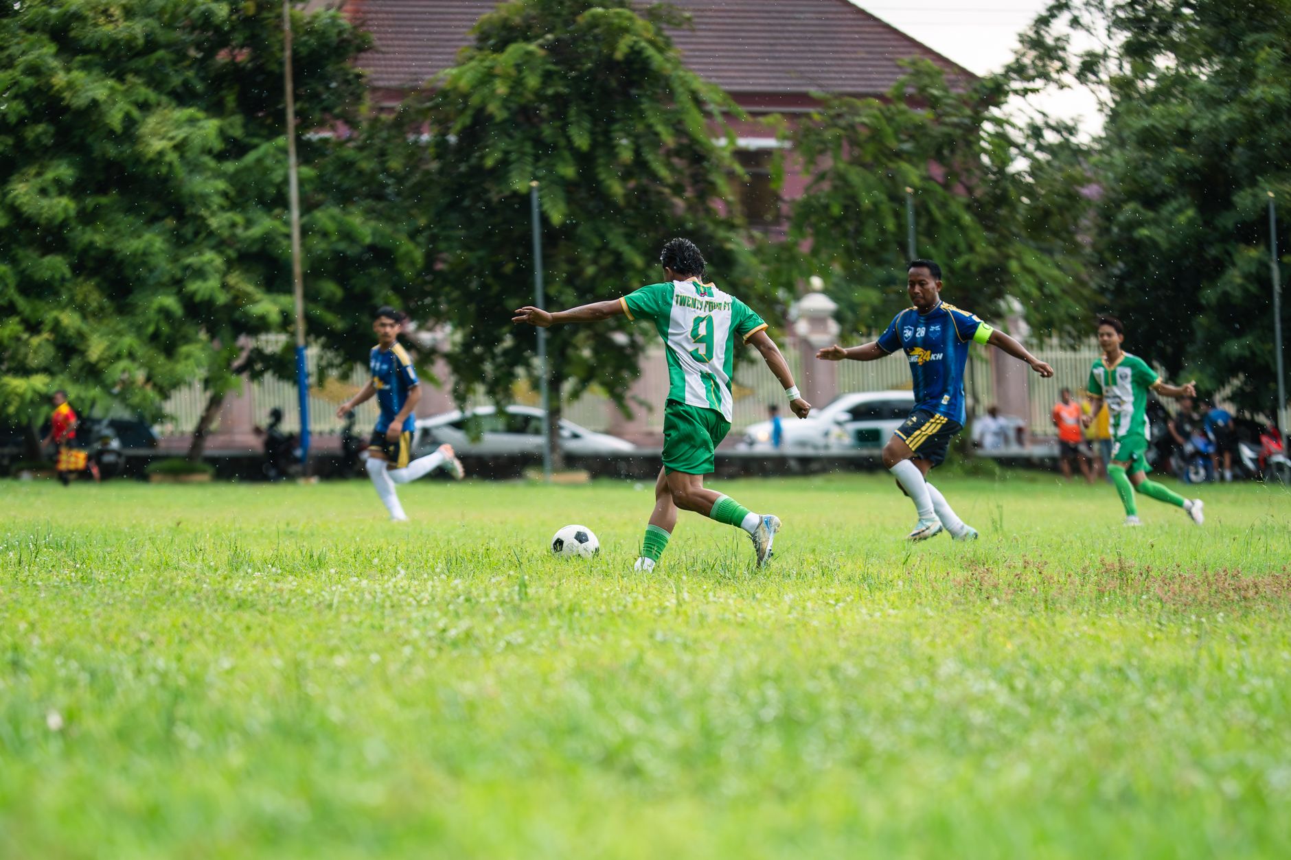 Pertandingan sepak bola dinamis yang dimainkan di lapangan berumput dengan para pemain yang antusias beraksi.