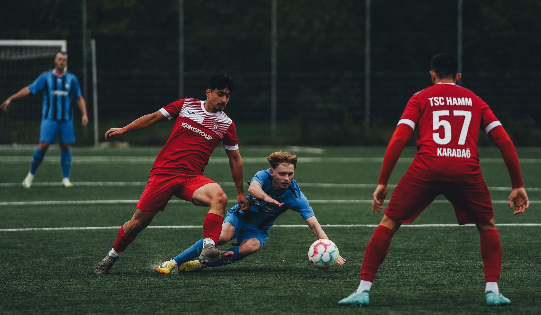 Pengambilan gambar dinamis pemain sepak bola saat beraksi selama pertandingan kompetitif di lapangan rumput.