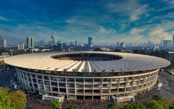 Pemandangan udara dramatis Stadion Gelora Bung Karno, Jakarta, dikelilingi oleh cakrawala perkotaan.
