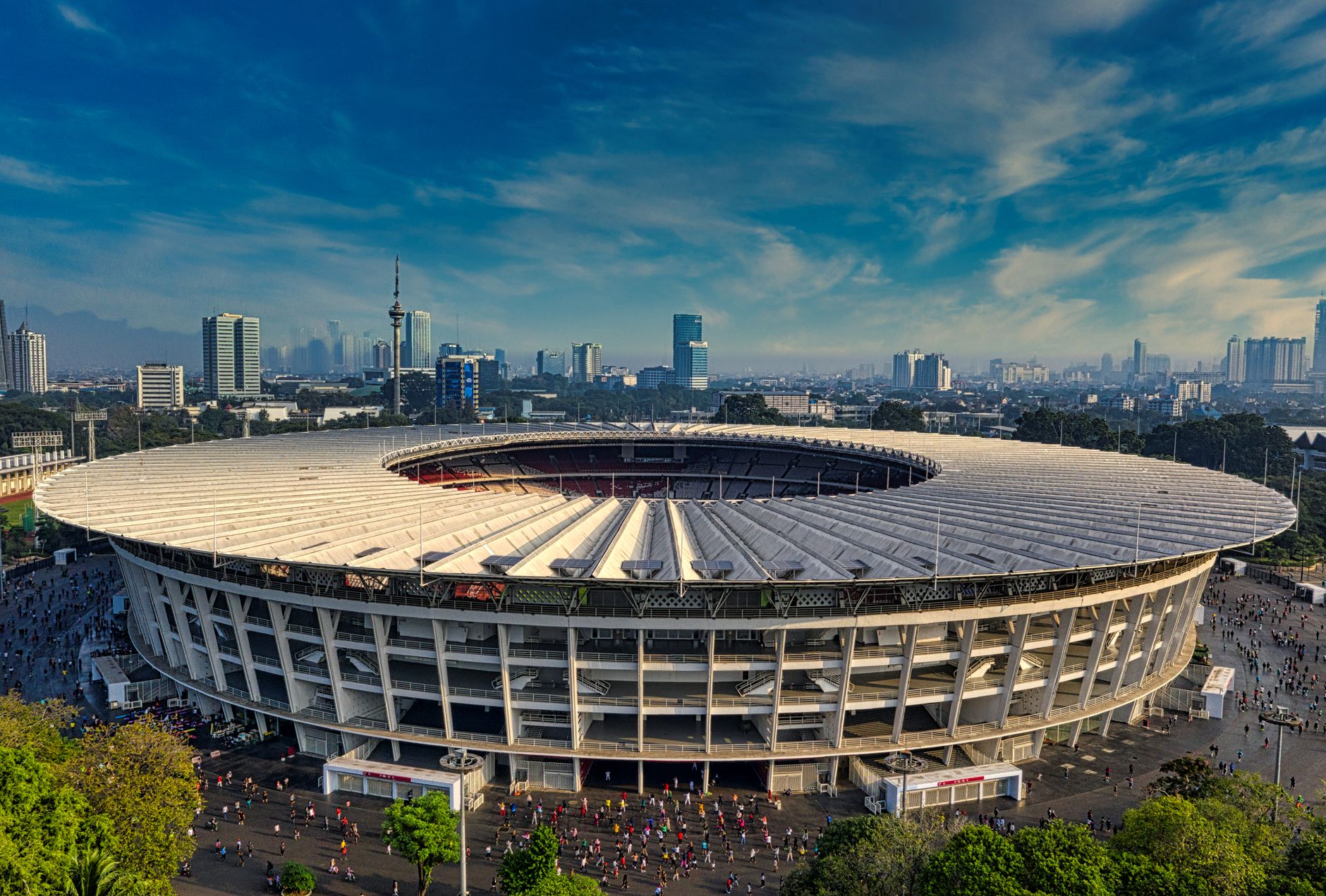 Pemandangan udara dramatis Stadion Gelora Bung Karno, Jakarta, dikelilingi oleh cakrawala perkotaan.