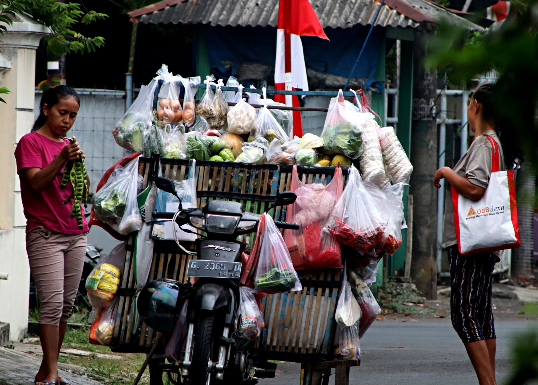 Seorang penjual jalanan di sepeda motor menjual sayuran dan buah segar di pasar terbuka yang meriah.