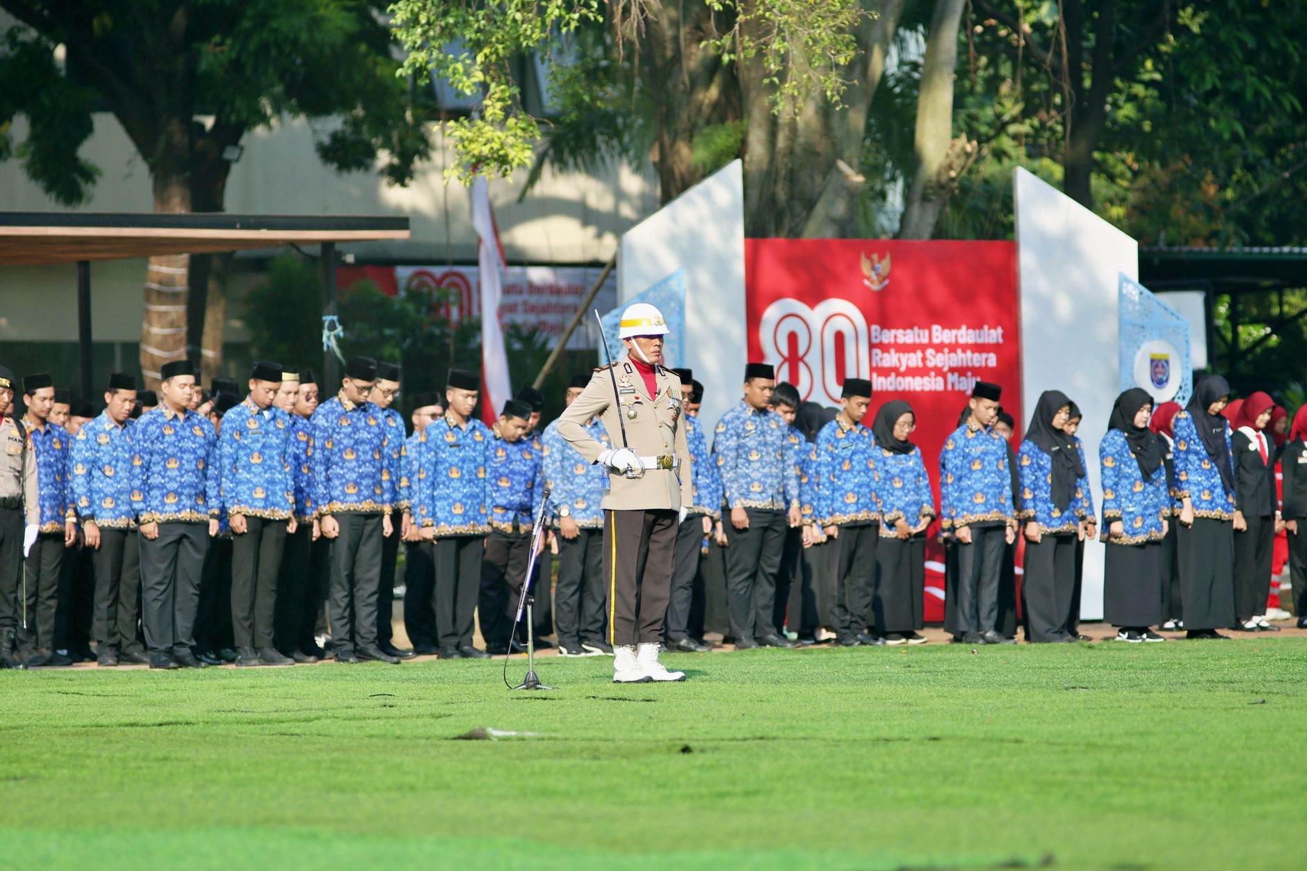 Acara Indonesia dengan peserta beruniform selama upacara bendera di luar ruangan.