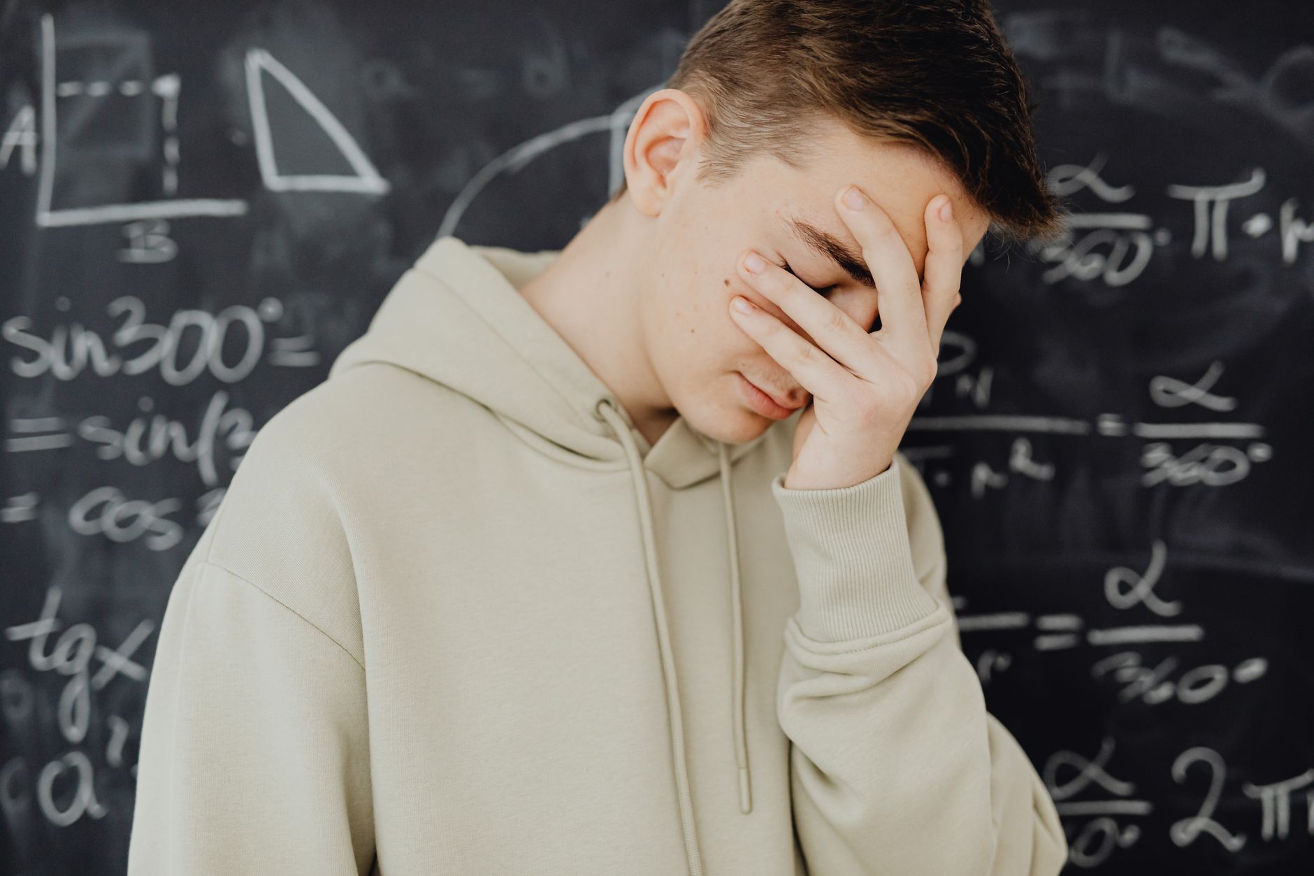 Pria muda yang terbebani oleh perhitungan matematis di papan tulis dalam pengaturan kelas.