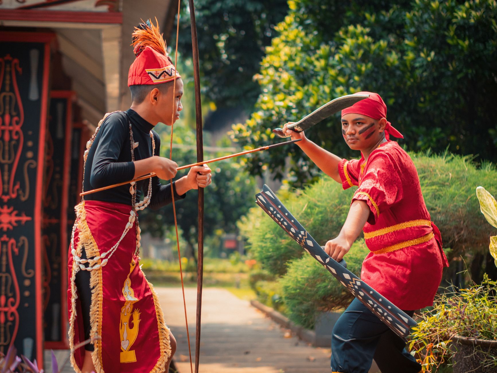 Dua pria terlibat dalam tarian prajurit tradisional Indonesia, menampilkan pakaian budaya dan senjata upacara.