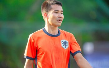 Pemain sepak bola pria mengenakan jersey oranye selama pertandingan di Hà Nội.