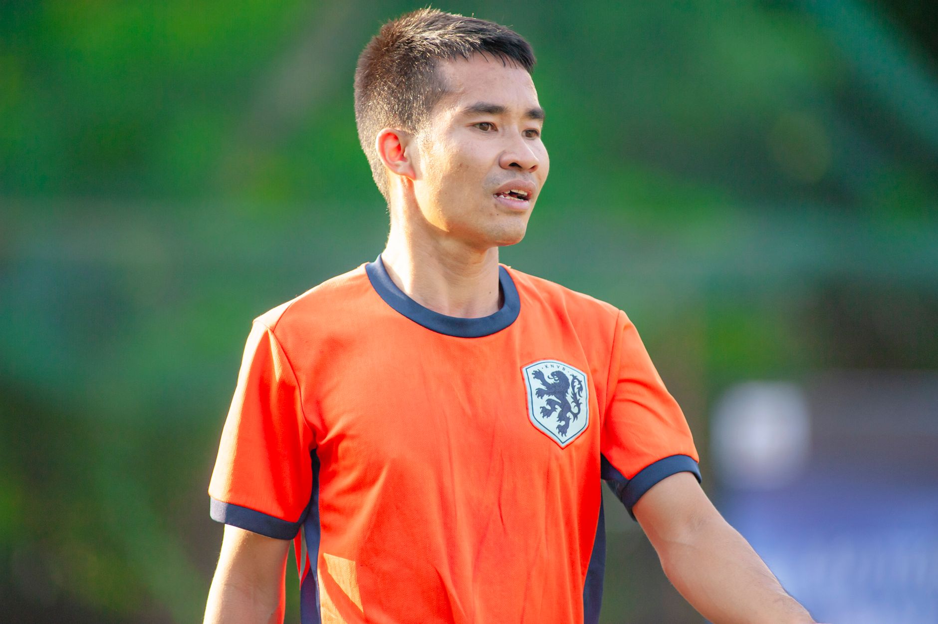 Pemain sepak bola pria mengenakan jersey oranye selama pertandingan di Hà Nội.