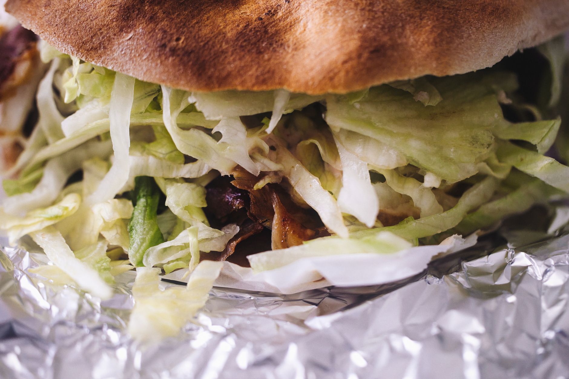 Foto close-up yang menggugah selera dari bungkus kebab döner dengan selada renyah, dibungkus dengan kertas timah, diambil di Kapfenberg, Austria.