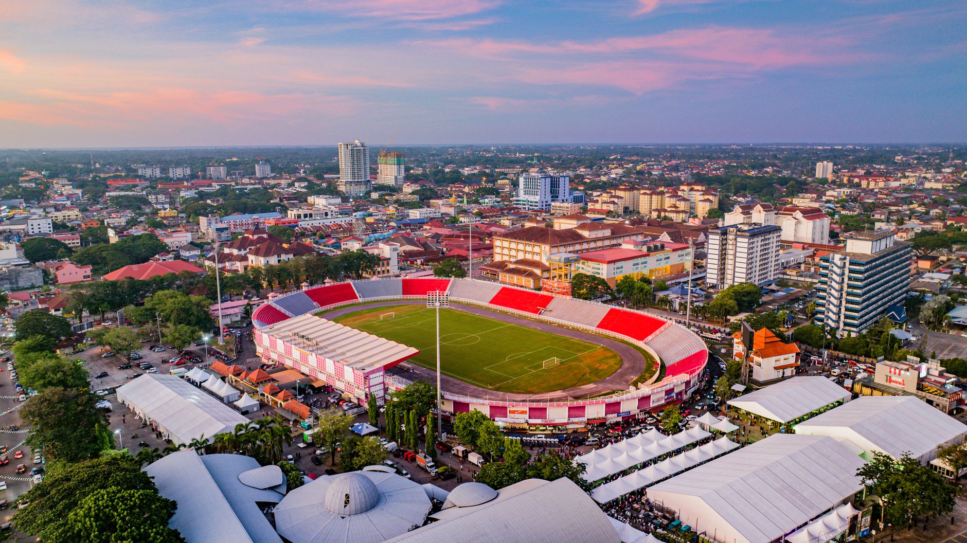 Pemandangan udara yang menakjubkan dari sebuah stadion di Kota Bharu, Malaysia saat matahari terbenam, dikelilingi oleh pemandangan kota.