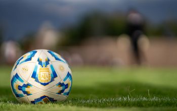 Close-up bola sepak resmi Argentina yang berada di lapangan hijau dengan latar belakang kabur.