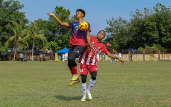 Dua pemain sepak bola muda bersaing ketat untuk merebut bola di lapangan terbuka.