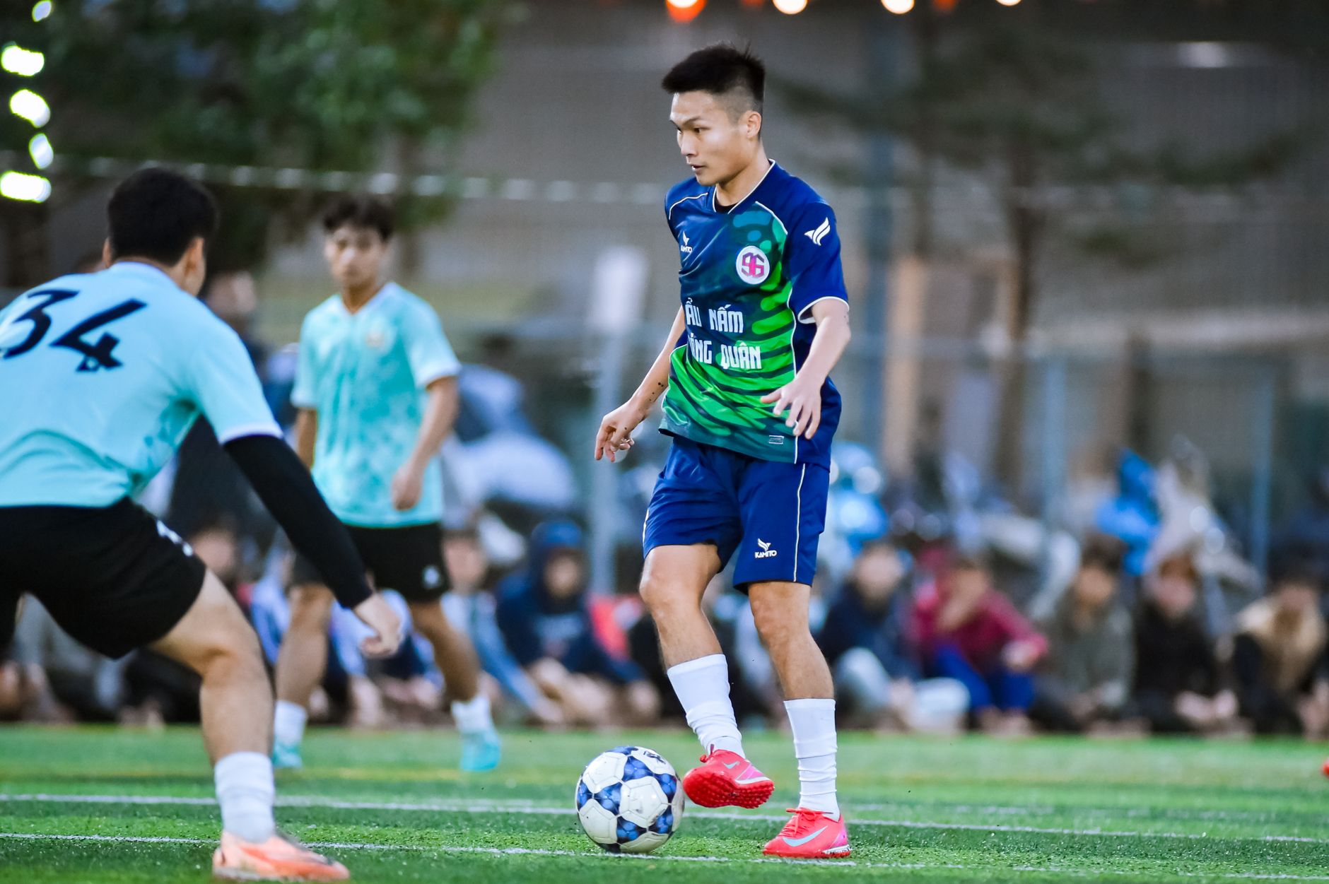 Pemain sepak bola muda beraksi di lapangan yang semarak di Hanoi, menunjukkan kerja sama tim dan atletisme.