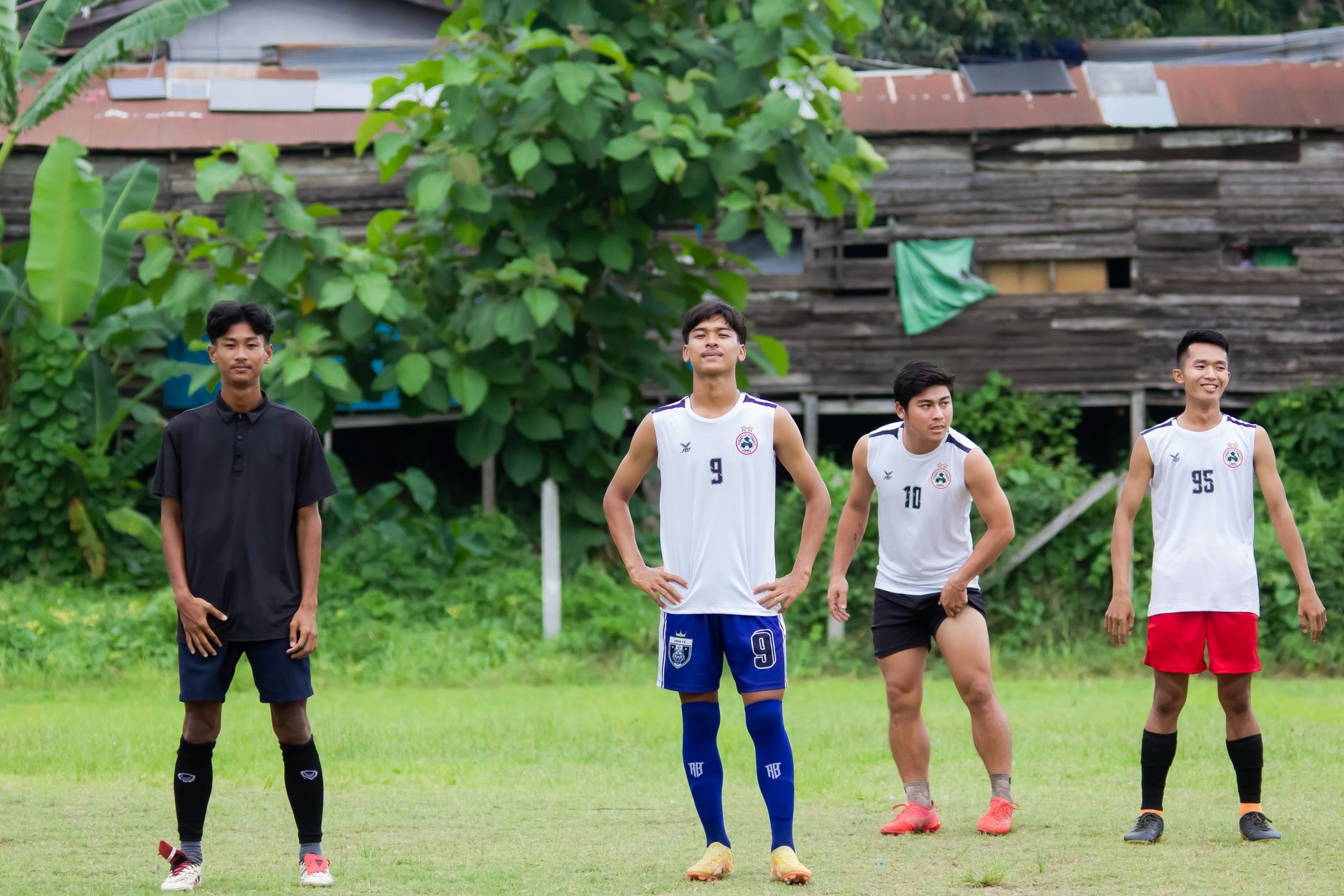 Sekelompok pemuda bersiap bermain sepak bola di lapangan hijau yang subur di Myawadi, Myanmar.
