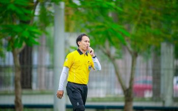Seorang wasit berbaju kuning meniup peluit selama pertandingan sepak bola di Hanoi, Vietnam.