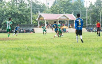 Para pemain sepak bola amatir berkompetisi di lapangan setempat pada hari hujan.