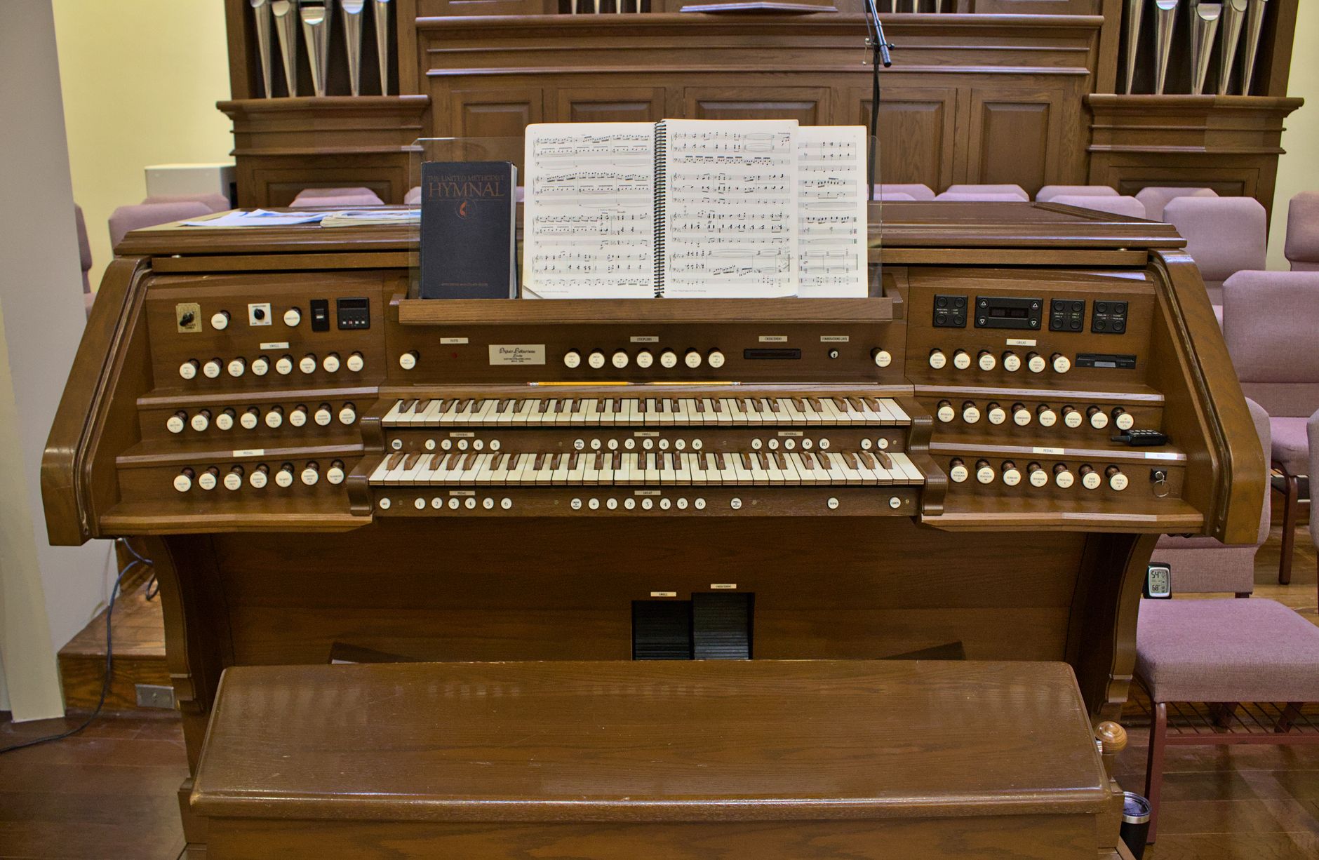 Sebuah organ pipa klasik yang elegan dengan buku himne terbuka dan lembar musik, siap untuk pertunjukan.