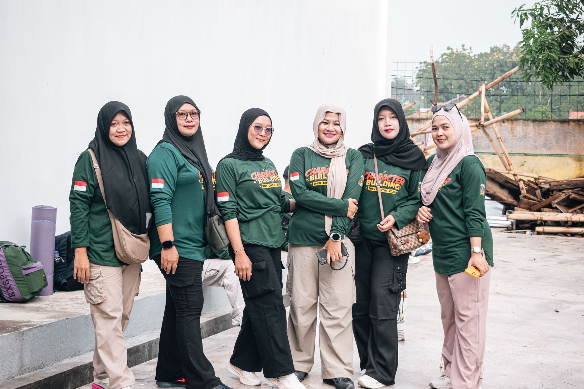 Enam wanita berpakaian hijau berkumpul untuk aktivitas pembentukan karakter di luar ruangan, menunjukkan kebersamaan dan persatuan.