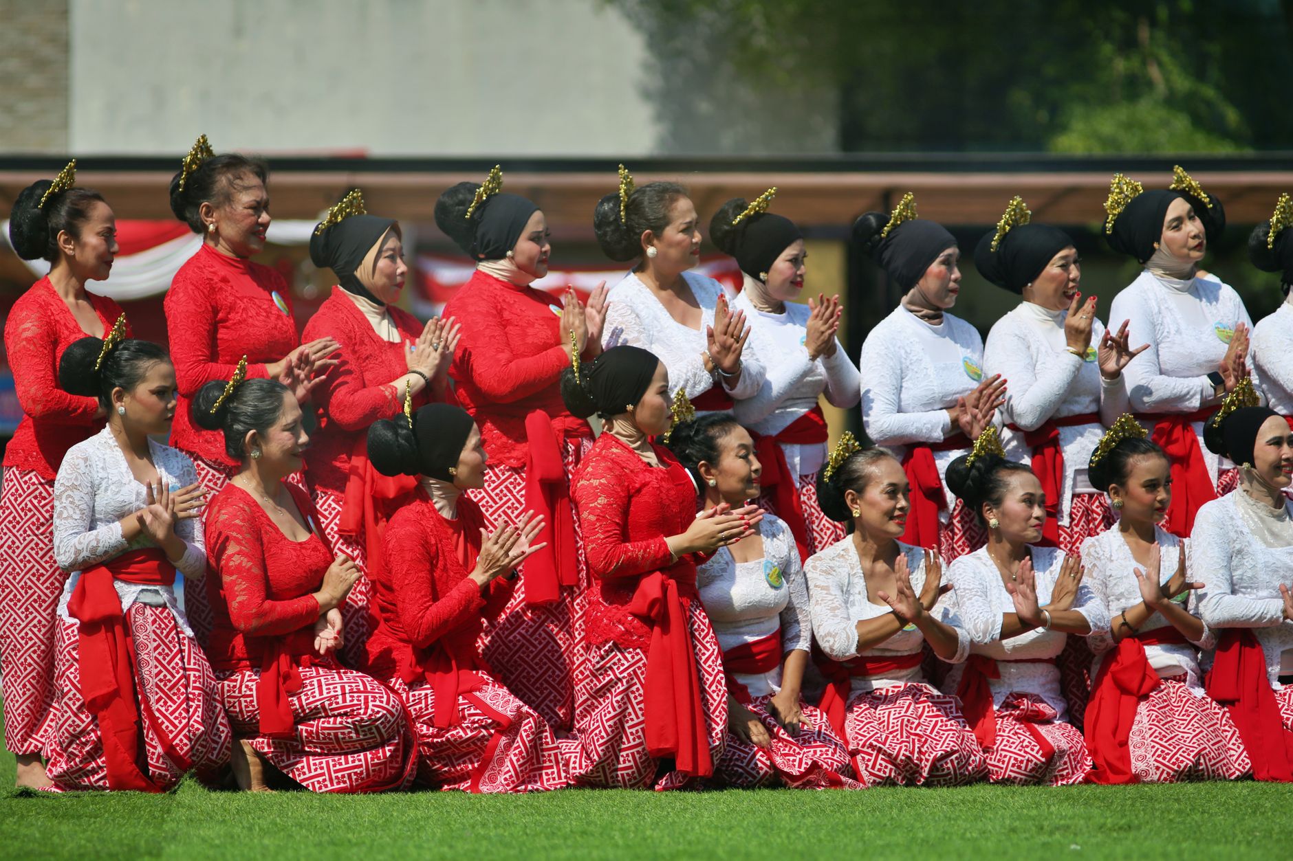 Sekelompok wanita mengenakan pakaian tradisional tengah menampilkan tarian budaya di luar ruangan.