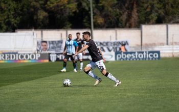 Aksi permainan sepak bola yang intens dengan pemain bergerak di bawah sinar matahari.