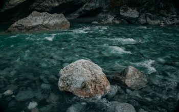 Sungai gunung yang tenang mengalir di atas batu-batu di lanskap indah Ossetia Utara.