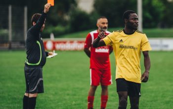 Wasit memberikan kartu merah kepada pemain sepak bola dalam pengaturan pertandingan luar ruangan.