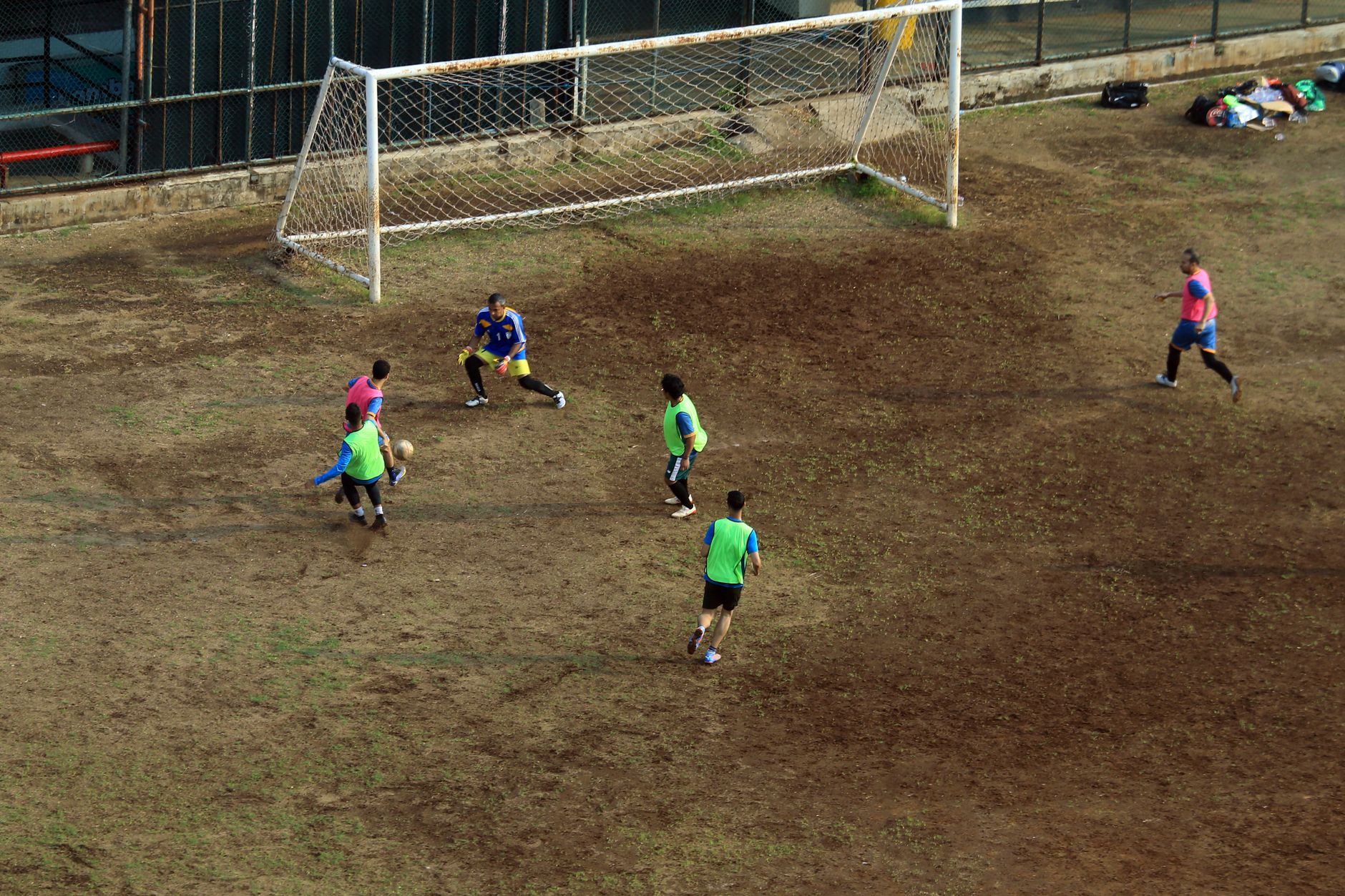Para pemain terlibat dalam pertandingan sepak bola di lapangan berlumpur, dilihat dari atas.