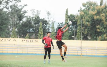 Atlet sedang bertindak selama sesi pelatihan sepak bola di luar ruangan, menampilkan lompatan energik dan kerja sama tim.