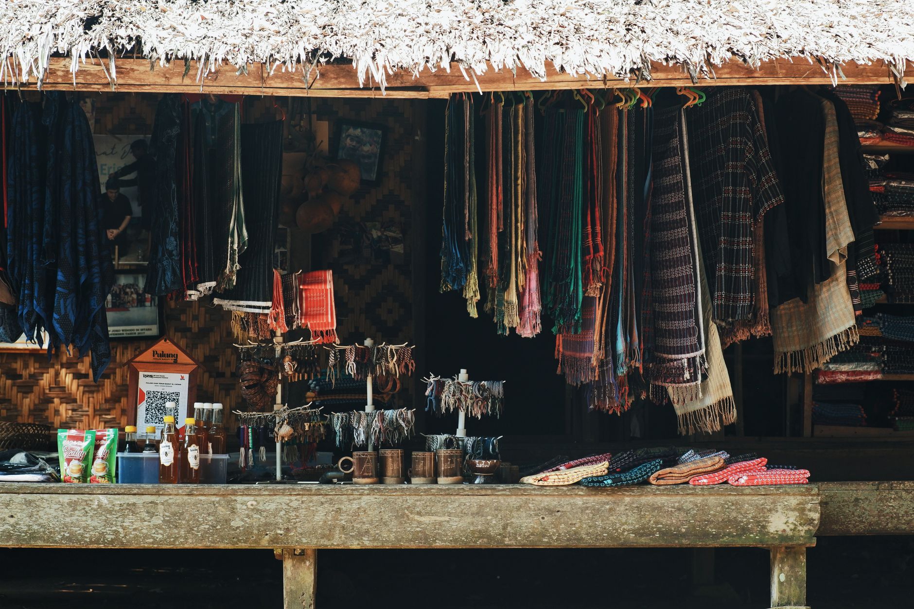 Sebuah kios pasar tradisional di Banten, Indonesia yang memajang tekstil warna-warni dan kerajinan tangan.