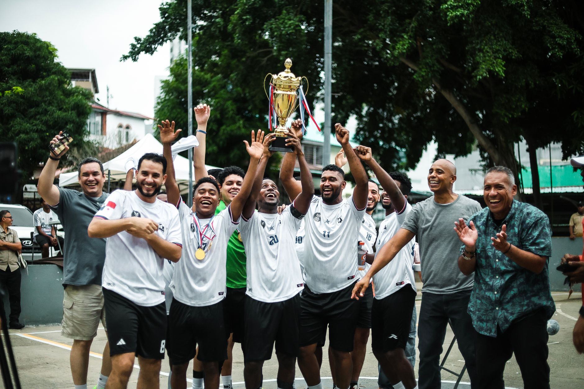 Sebuah tim sepak bola yang gembira merayakan kemenangan mereka dengan trofi di luar ruangan di Kota Panama.