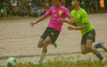 Dua pemain muda putra berkompetisi dalam pertandingan sepak bola yang meriah di Myawaddy, Myanmar.