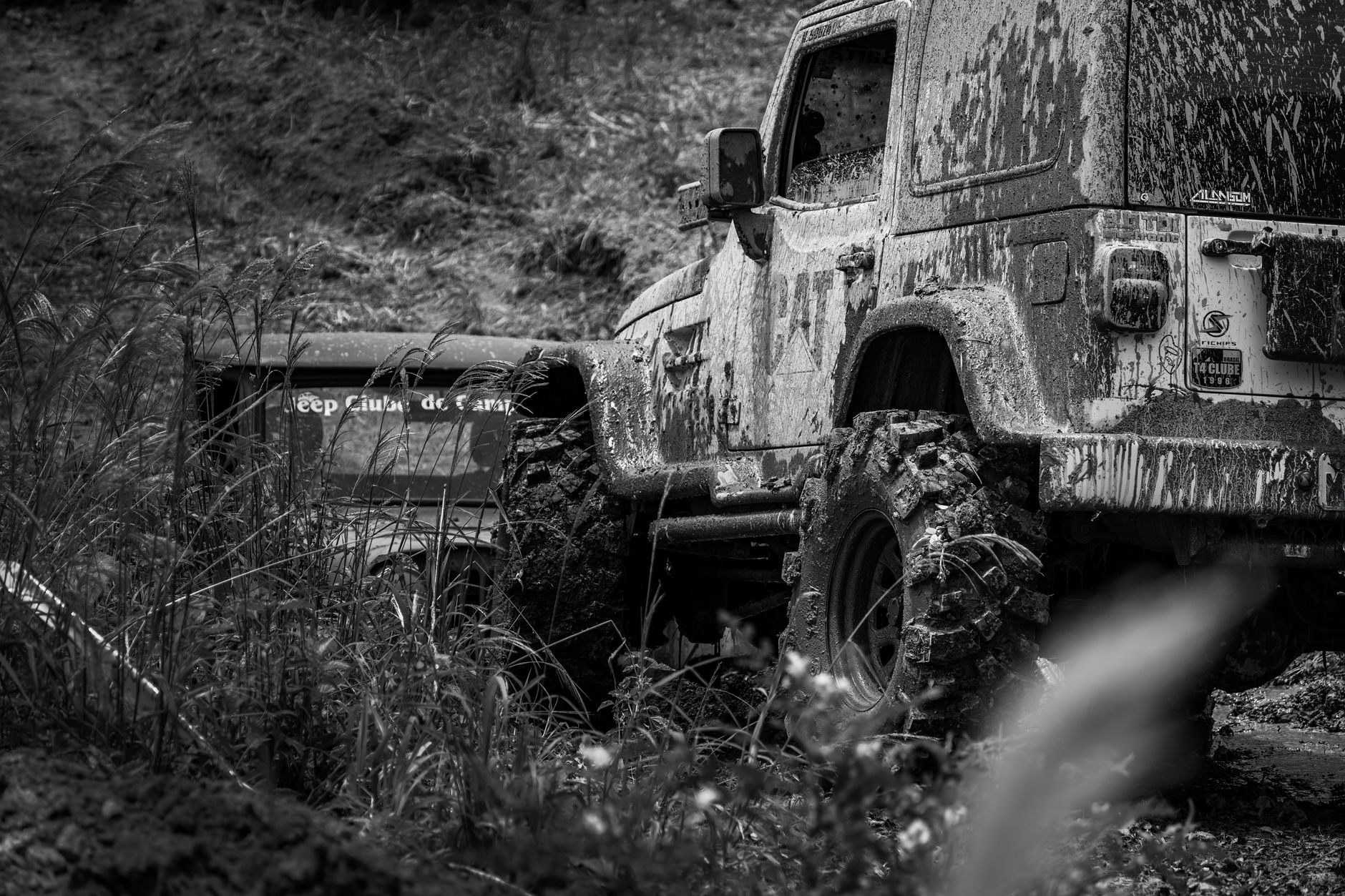 Sebuah jeep kotor yang menghadapi medan off-road di lingkungan pedesaan, menunjukkan petualangan dan ketangguhan.